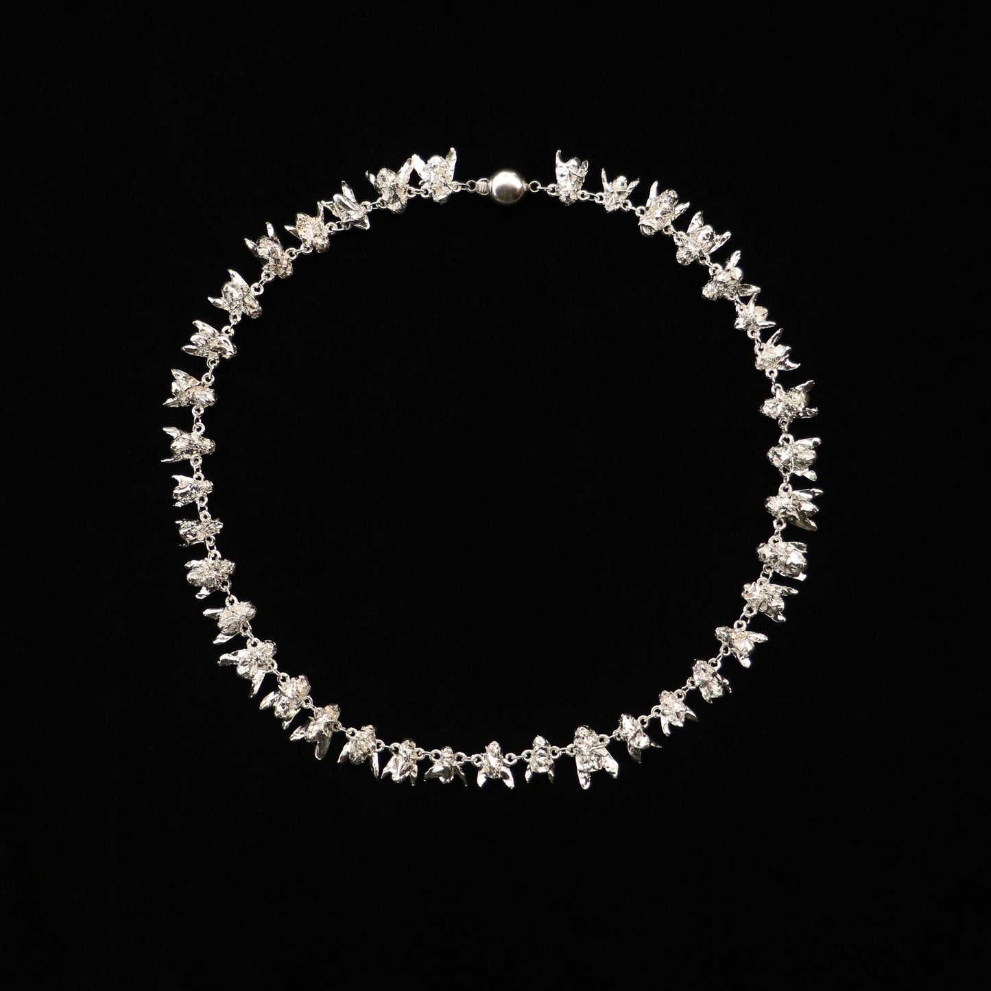 A sterling silver necklace with a series of fly-shaped charms linked together, displayed against a black background.