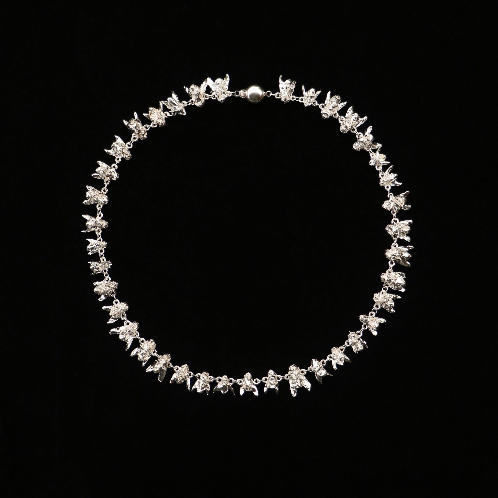 A sterling silver necklace with a series of fly-shaped charms linked together, displayed against a black background.